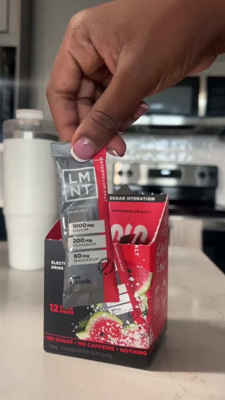 An LMNT electrolyte stick being lifted from the box on a kitchen counter